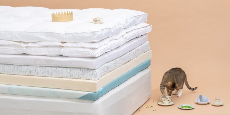 Quilted mattress topper on a firm mattress in a bright bedroom